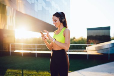  Aktif olarak çalışan genç, zayıf bir kadın stadyumda spor yapıyor, vücudunun alt kısımları için egzersiz yapıyor, Kafkasyalı bir kız forma hedeflerini koruyor, enerji için çalışıyor, kulaklıkla müzik dinliyor.