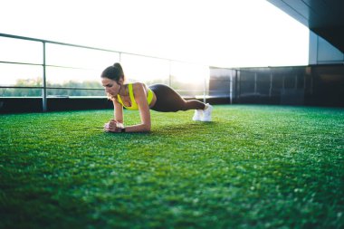  Aktif olarak çalışan genç, zayıf bir kadın stadyumda spor yapıyor, vücudunun alt kısımları için egzersiz yapıyor, Kafkasyalı bir kız forma hedeflerini koruyor, enerji için çalışıyor, kulaklıkla müzik dinliyor.