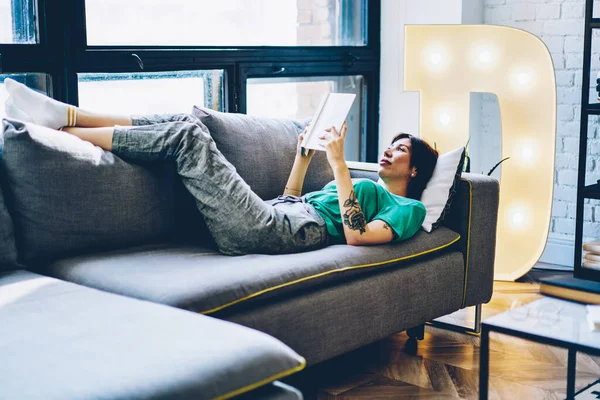 Gündelik giyinmiş güzel, ciddi bir yeniyetme kız rahat koltukta oturup kitap okuyor. Kafkasyalı 20 'li yaşlarda bir kadın oturma odasındaki kanepede uzanmış ilginç edebiyattan zevk alıyor.