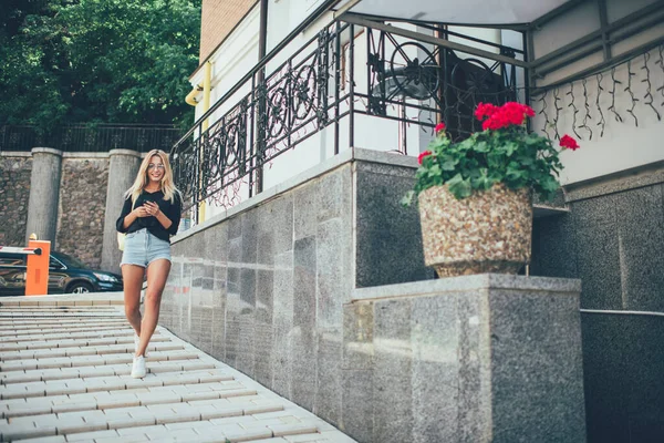 휴대폰 기기를 여성이 휴가철에 도시를 탐험하는 즐거운 선글라스를 도시를 거닐며 — 스톡 사진