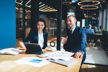 Ofisteki beyin fırtınası toplantısında iş ortaklarıyla dijital tablet kullanarak neşeli erkek ve kadın girişimciler, iş birliği ve gülümsemeyi tartışan mutlu meslektaşlar