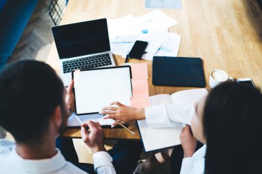 İş adamlarının internet reklamları için dokunmatik alandaki veri sitesinde arama yapmalarına arka planda, erkek ve kadın meslektaşlar sahte cihazlar kullanarak şirket fikirleri üzerinde işbirliği yapıyorlar.