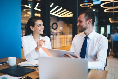 Neşeli şirket çalışanları modern teknoloji ve fikirleri tartışarak masada oturuyorlar, profesyonel analistler iş projesinde işbirliği için beyin fırtınası toplantısının keyfini çıkarıyorlar.