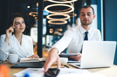 Beyaz yöneticiler 30 'lu yaşlarda resmi giysiler içinde masa başında oturmuş şirket çalışmalarını planlıyorlar. Çalışma saatleri boyunca çalışan erkek ve kadın çalışanlar teknolojiyi kullanıyorlar.