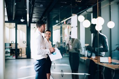 Neşeli kadın yönetici 30 'lu yaşlarda, modern ofisteki erkek ortakla işbirliği sırasında iş hakkında konuşuyor başarılı yönetici işverenler şirket şirketinde beyin fırtınası yapıyorlar.
