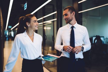 Başarılı deneyimli 30 'lu yaşlarda çalışanlar şirket koridorundaki müzakereler hakkında konuşuyor, neşeli erkek ve kadın ortaklar iş birliği stratejisini dijital tablet kullanarak konuşuyorlar.