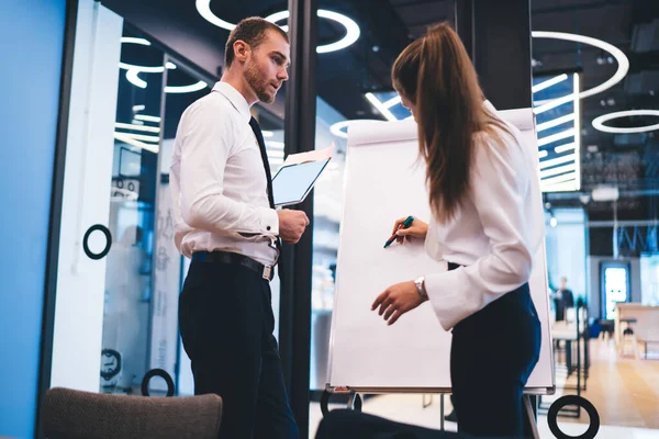 Profesyonel ekonomist, ortaklarla brifing sırasında proje için fikirler yazmak için beyaz tahtayı kullanıyor. Başarılı iş adamları birlikte çalışarak şirkette çözümler arıyorlar.