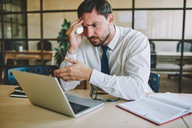 Kafası karışmış erkek CEO ofis içi çalışma saatlerinde masa başında oturmuş web işi problemini çözüyordu. Resmi kıyafetli mutsuz bir Kafkas çalışanı, kötü haberlerle dolu bir e-posta aldı.