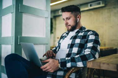 Düşünceli hippi çocuk internetteki bilgisayar kurslarını öğrenmeye ve izlemeye odaklanmış. Kulaklıklı yakışıklı bir erkek, internet sitelerinde serbest iş ararken radyo dinliyor.