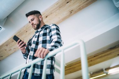 Akıllı telefondan akıllı telefon dinleyen, kulaklıkla müzik indiren, modaya uygun giyinen, gündelik giyinen, modern aletleri kullanarak internetten sohbet eden yakışıklı bir hippi.