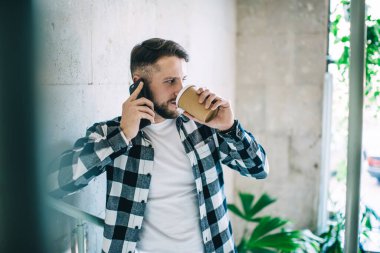Gündelik hayattaki kendine güvenen erkek cep telefonu konuşmaları sırasında tek kullanımlık bardaktan içki içiyor. Modern kafeteryadaki kahve molasında ciddi bir yenilikçi adam milenyum boyunca akıllı telefon görüşmesi yapıyor.