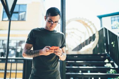 Görme düzeltmesi için gözlüklü beyaz tenli adam mobil uygulama için gelen uyarıyı okuyor, e-postaları kontrol eden yakışıklı genç adam cep telefonundan 4G 'ye bağlanıyor.