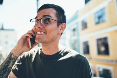 Gözlüklü neşeli hippi, güneşli bir günde akıllı telefon uygulamasına bağlı arkadaşlarıyla grup sohbetinde vakit geçirmekten keyif alıyor. Uluslararası kullanım için internette gezinme kavramı.