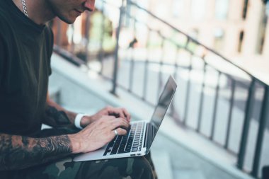 İnternetteki medya dosyalarını araştıran genç erkek programcının kesilen görüntüsü modern dizüstü bilgisayardaki yüksek hızlı kablosuz internet sitesine bağlı ana sayfa için ilginç bir tasarım yaratıyor.