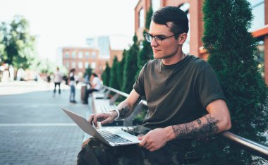 Gözlüklü konsantre erkek öğrenci, üniversitedeki devlet internetine bağlı üniversite kursuna ilişkin bilgilerle çalışan, internet sitesinden haber okuyan, bilgisayar ışığından gözler sağlıyor.