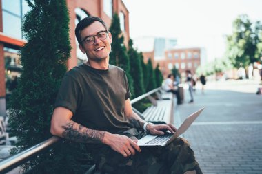 Gözlük takan, gözlüklü, dizüstü bilgisayarla çalıştığı için kameraya gülümseyen, netbook 'a gülümseyen, gözlüklü mutlu bir adamın portresi.