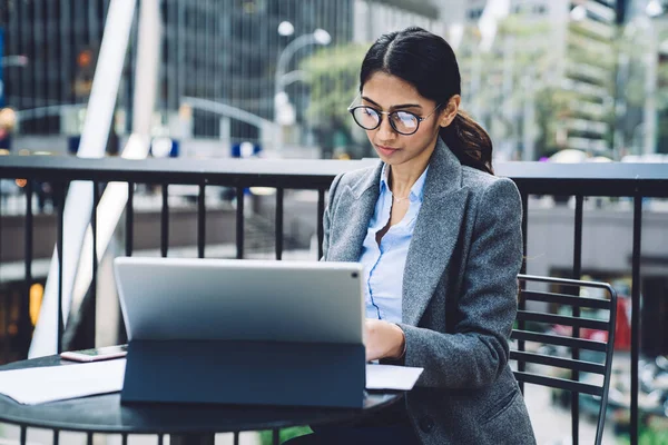 Zarif kıyafetli, gözlüklü, kendine güvenen bir iş kadını New York 'un terasındaki tablette sörf yapıyor. 