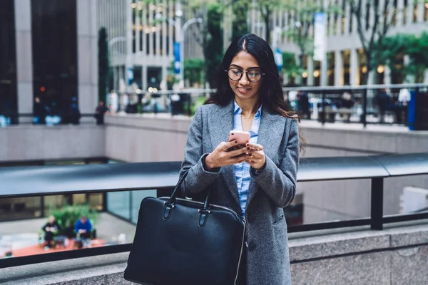 Modern Trendi Etnikai Kabátban Szemüvegben Áll Utcán Szörfözés Mobiltelefon Ellen — Stock Fotó