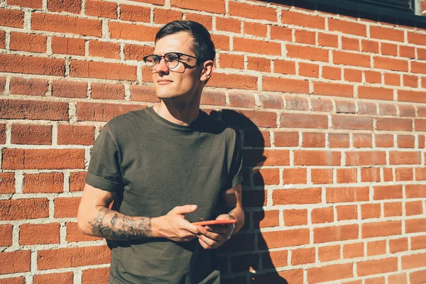 Thoughtful Hipster Guy Spectacles Pondering Notification Smartphone While Standing Wall — Stock Photo, Image