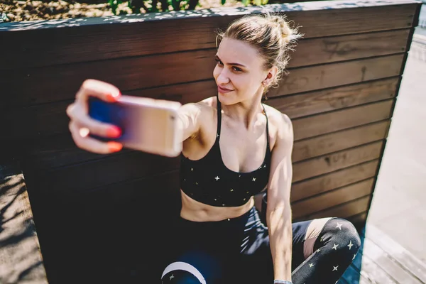 Shora Sebevědomá Atletka Aktivním Stylovém Oblečení Zkříženýma Nohama Selfie Mobilním — Stock fotografie