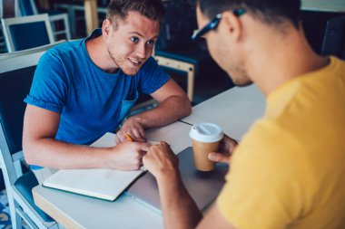 Günlük giysiler içinde mutlu bir işçi not defterine not defteri yazarak kafede sıcak bir şeyler içen bir ekin partneri yaratıyor.