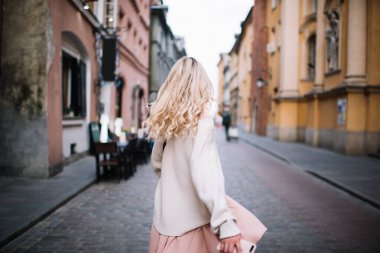 Modayı takip eden, gündelik kıyafetli, cep telefonlu, sarışın, rüzgarda savrulan, şehir arka planında gezen modern bir kadının arka planı. 