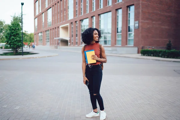 Wesoła Młoda Afroamerykanka Studentka Fryzurą Afro Odwraca Wzrok Trzymając Telefon — Zdjęcie stockowe