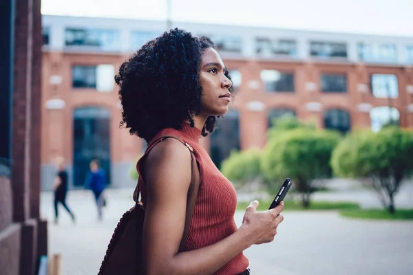 站在校园内大学大楼附近的非洲裔美籍少女用智能手机发短信的侧影 — 图库照片