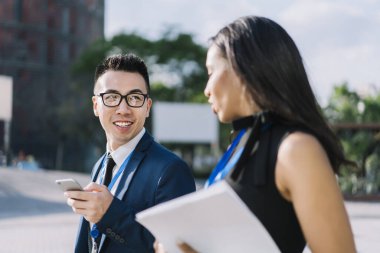 Resmi giyinmiş, gözlüklü, İspanyol bir kadınla iletişim kuran, sokakta yürüyen, birbirine bakan genç bir adam.