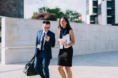 Resmi kıyafetli, çantalı, neşeli İspanyol bir kadınla konuşan modern şehrin caddesinde kahve içen heyecanlı bir adam.