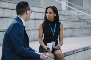 Şık giyinmiş İspanyol bayan menajer sallanan tribün stadyumunda dinlenirken yeni erkek çalışana tavsiye veriyor. 