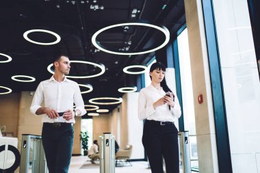 Modern ofis koridorlarında akıllı telefonlar üzerinde sörf yaparken şık resmi kıyafetler giyen hasretli meslektaşlar turnikeden geçiyorlar.