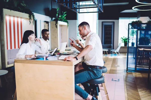 現代のオフィスで文書と机に座っている間に会話やジェスチャーを持つ正式な服の意図多民族オフィスの労働者の側面図 — ストック写真