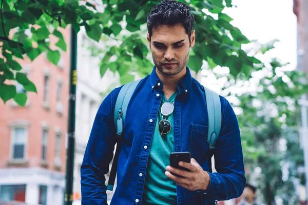 穿着粗斜纹棉布衬衫的时髦年轻人站在纽约市的大街上 在城市背景下冲浪手机 — 图库照片