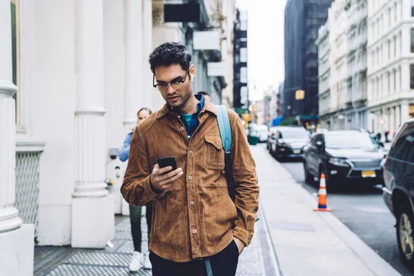 Konzentrierter Gutaussehender Erwachsener Mann Mit Brille Und Rucksack Tippt Smartphone — Stockfoto