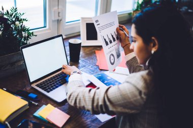 Laptop kullanan, serbest proje analizi yapan, kafedeki masada oturan, ekin işleriyle uğraşan bir kadının arka planı.