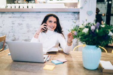 Kafeteryanın mutlu yöneticisi organizasyon bilgileri için cep telefonu iletişimi kuruyor, Kafkas kadın serbest bilgisayar ve eğitim kitabıyla masada oturuyor ve telefonla konuşuyor.