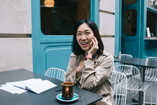 Verrast Aziatische Vrouw Trench Praten Mobiele Telefoon Lachen Terwijl Ontspannen — Stockfoto