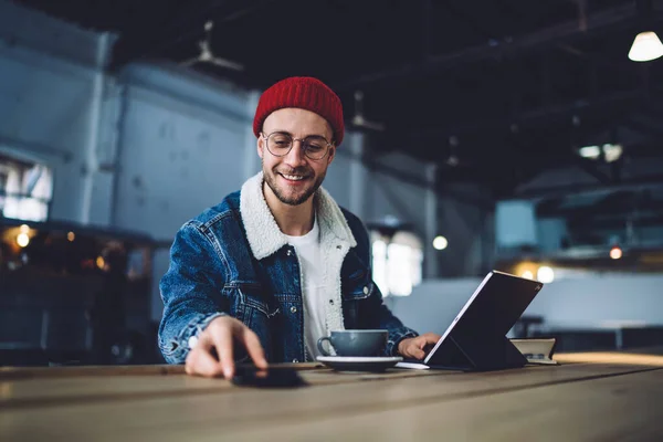 Pozitivní Pohledný Muž Ležérní Oblečení Surfování Internetu Smartphonu Zatímco Sedí — Stock fotografie