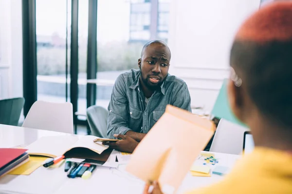 불편을 아프리카 미국인 남성은 평상복을 탁자에 반대되는 사무실 공간에서 동료와 — 스톡 사진