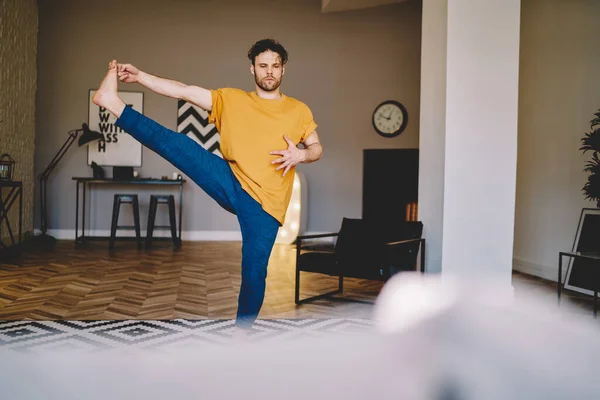 Konzentrierter Typ Lässiger Kleidung Mit Erhobenem Bein Der Auf Einem — Stockfoto