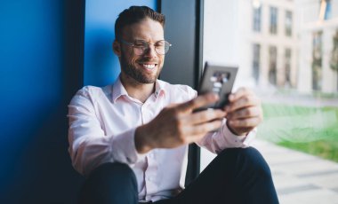 Gezici sohbetler sırasında komik mesajlar okuyan, gözlüklü beyaz blogcu, boş zamanlarında cep telefonuyla internet ağı kurmak için web içeriğini araştırıyor.