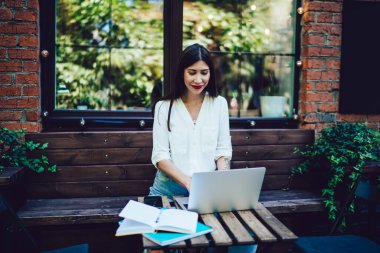 Neşeli Latin menajer birlikte çalışan sokak kafesinde modern dizüstü bilgisayar üzerinde çalışıyor, hipster kız sosyal medya ağında bilgi alışverişi yaparken e-kitap üzerinden bilgi topluyor.
