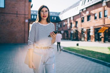Kaygısız kadın milenyumu dijital akıllı telefon aygıtı ve netbook 'a odaklanın ve öğrenim için kameraya bakın, cep telefonlu güzel İspanyol blogcunun yarım boy portresi