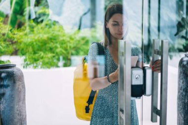 Ciddi sarışın 20 'li yaşlarda bir kadın açık kapılar takıyor. Şifreli anahtarlar binanın dışında duruyor. Moda bir sırt çantasıyla.