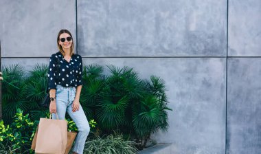 Yarım boy gülümseyen beyaz tenli sarışın kadın portresi elinde alışveriş çantaları, mutlu 20 'li yaşlardaki kadın alıcılar perakende satışından memnun ve kameraya bakan alıcılar.