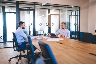 İnternette araştırma yapmak ve verileri paylaşmak için bilgisayarı ve dokunmatik bloknotu kullanan başarılı erkek meslektaşlar, ofiste ortaklık stratejilerini tartışan işadamları