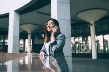 Binlerce yıllık olumlu genç kız öğrenci şehir ortamında cep telefonuyla konuşuyor, gülümseyen beyaz hippi kız akıllı telefon konuşmaları yapıyor, gezinti tarifeleriyle tatmin oluyor.