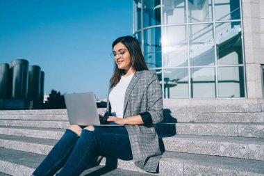 Uzak iş sitelerinde dizüstü bilgisayar kullanan başarılı genç bayan serbest yazar, şehir ortamlarında klavye kullanıyor, pozitif kadın öğrenci güneşli havadan hoşlanıyor ve webinar seyrediyor. 