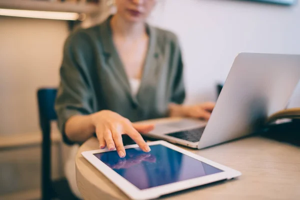 職場でラップトップを使用している間 プライベートアカウントのパスワードを入力してタブレット画面に触れるテーブルに座っているクロップ女性 — ストック写真